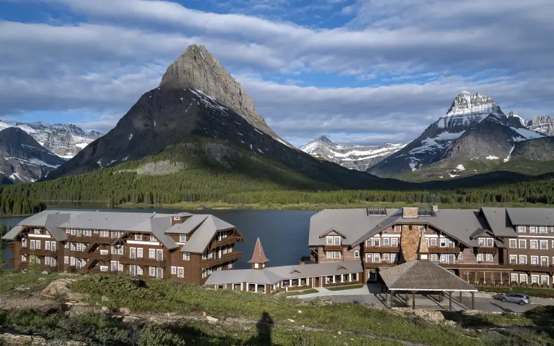 Many Glacier Hotel on a lakeshore below snow-streaked peaks in Glacier National Park